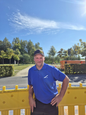 Der Betreuer Michale Kollmann steht vor dem Unimog-Parcours und trägt ein blaues LBM-Poloshirt.