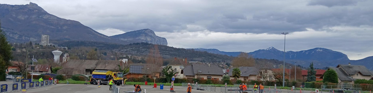 Ein gelber Lkw fährt im Unimog-Geschicklichkeitsparcours. Im Hintergrund ist eine Berglandschaft zu sehen. 