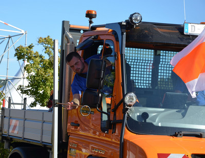 Der Beifahrer greift durch das Fenster des Unimogs nach einem Stahlring. 