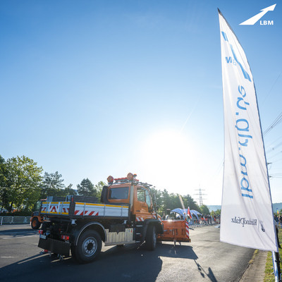 Blick von hinten auf den Unimog auf dem Parcours bei der Deutschen Meisterschaft im Schneepflugfahren 2023 in Koblenz, rechts im Bild eine weiße LBM-Beachflag.