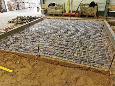 Blick in die Pflasterhalle der überbetrieblichen Ausbildung, hier wird gerade ein Stück Straße gepflastert