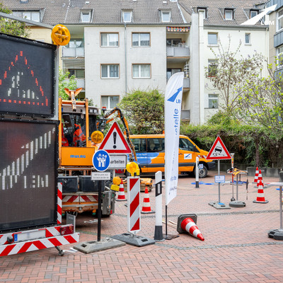 Blick auf den Innenhof der LBM-Zentrale: orangene Fahrzeuge im Hintergrund und verschiedene Verkehrszeichen im Vordergrund, die den Einstieg in den Parcours markieren