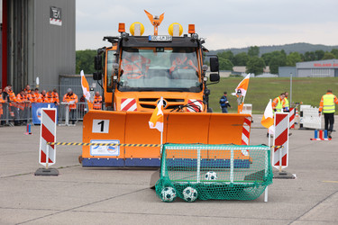 Der Unimog befördert einen Fußball bei dem Hindernis "Uni-Soccer" in ein Tor.